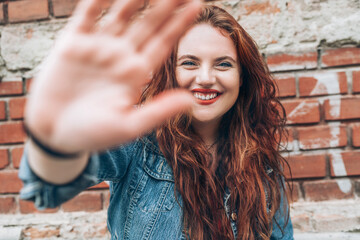 Fashion portrait of sincerely smiling red curled long hair caucasian teen girl with applied red...