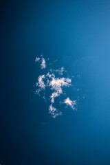 portrait image of a cloud scattered by the wind under a blue gradient sky.