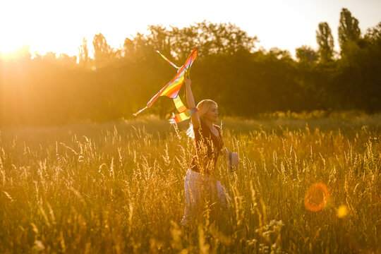 Portrait of a young and carefree woman launching kite on the greenfield. Concept of active lifestyle in nature