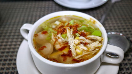 sausage soup with a sprinkling of fresh shredded chicken in a white bowl