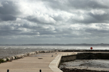 Carrickfergus is a large town in County Antrim, Northern Ireland. It sits on the north shore of Belfast Lough, 11 miles from Belfast. Featuring coastline with light house and stormy clouds.