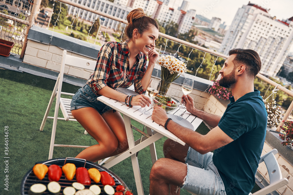 Sticker cute young couple in casual clothing enjoying romantic dinner and smiling while enjoying romantic di