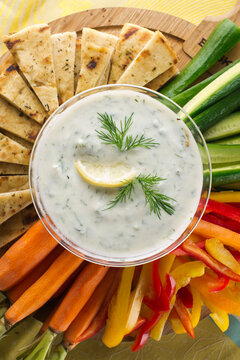 Tzatziki. Traditional Greek Or Turkish Homemade Dip. Made With Greek Yogurt, Cucumbers, Lemon Juice, Olive Oil And Dill. Served With Mini Rainbow Carrots & Crispy Pita Chips On A Wooden Cutting Board