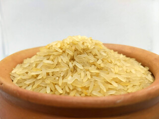  A bowl filled with uncooked white rice. On top of a white wood table   