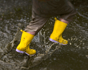 Yellow rain boots splashing in a puddle