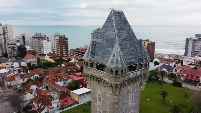 Aerial drone view of old Water Tank tower building called Torre Tanque - one of popular city landmark. Panoramic city view and ocean. Drone fly above old tower. Mar del Plata, Argentina.
