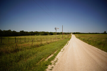 Fototapeta na wymiar A farm windmill in the Kansas countryside along a dirt road.