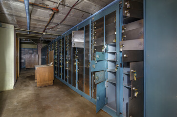 Old metal cabinets with deposit boxes covered with rust in an abandoned bank depository
