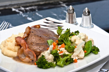 Filete mignon envuelto en tocino con puré de papa y verduras cocidas 