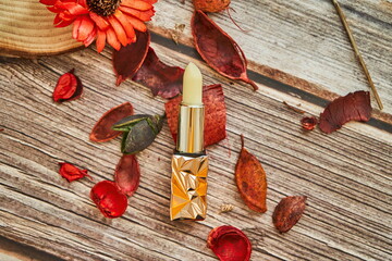 A lip balm on a board with lots of bits of dried flowers next to it.