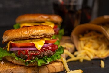 Fast and tasty food, hamburger or burger with french fries and sonova with ice on a black background with blurFast and tasty food, hamburger or burger with french fries