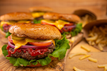 Fast food, burger with potatoes, wooden background with blur