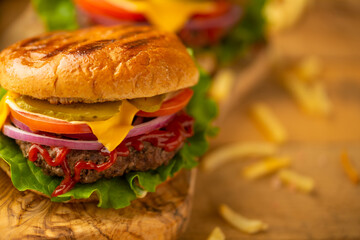 Hamburger or burger with french fries on a wooden background, tasty and unhealthy food, fast food