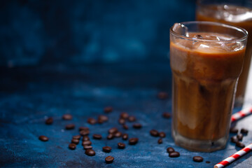 Cold cool coffee with milk and ice, against the blue wall, cool summer drinks