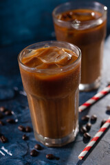 Cold cool coffee with milk and ice, against the blue wall, cool summer drinks