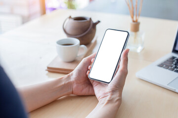 cell phone mockup image blank white screen.woman hand holding texting using mobile on desk at coffee shop.background empty space for advertise.work people contact marketing business,technology