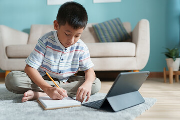 Education. Asian boy learning and doing homework with the online teacher on tablet digital at home