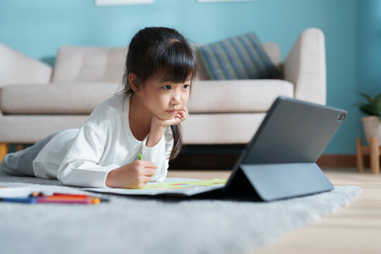 homeschooling. Asian little girl doing drawing with  online teacher on tablet digital