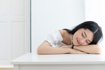 Young beautiful girl in a white lace shirt lies on a table in the room on a white background, sleepy, in the morning.