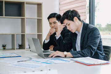 Stressed young asian business man working on laptop computer at office.