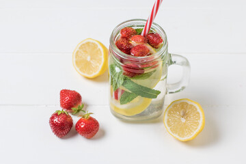 A mug with a red tube and a cold drink made of lemon and berries.