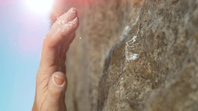SLOW MOTION, LENS FLARE, MACRO, DOF: Woman slips while trying to grab a crimp hold during a rock climbing trip. Climber slips and falls after attempting to grip a small edge hold while scaling a cliff