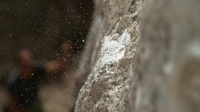 SLOW MOTION, MACRO, DOF: Magnesium particles fly around a crimp hold after climber slips and falls off a cliff. Climbers scaling a difficult boulder leave a thick layer of chalk on a small edge hold.