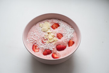 Delicious smoothie bowl in pink bowl on a white table
