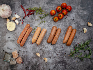 top view of various suasage type with herbs on grey concrete background. food preparation concept.