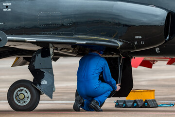 Aircraft engineer working in the undercarriage bay of a military jet trainer.