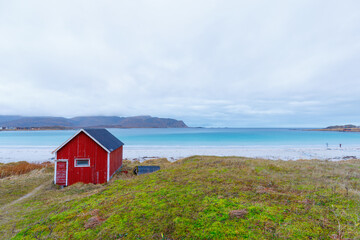 Blue water at beach Rambergstranda with typical red fisher hut in Ramberg, Norway