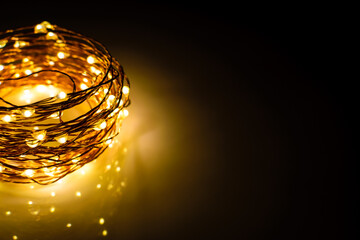 Yellow colored light chain for decoration placed on a reflective surface. Space for text in the...