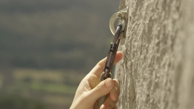 SLOW MOTION, CLOSE UP, DOF: Rock climber clips a carabiner into a bolt screwed into the cliff. Lead climber quickdraws a carabiner into a bolt. Unrecognizable fit woman clips carabiner into a bolt.