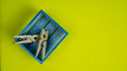 Bright yellow background with small wooden tray and clips for Art development 