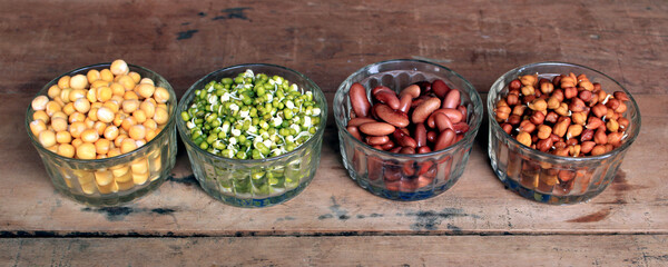 Collection of legumes (chickpeas, green peas, green mung beans, Red Kidney, Dry peas)in different bowls isolated on wooden background.