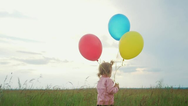 daughter little girl fun runs with balloons a on her birthday outdoors by field. dream happy family concept. child girl kid day. child is lifestyle running and balloons on a background of blue sky