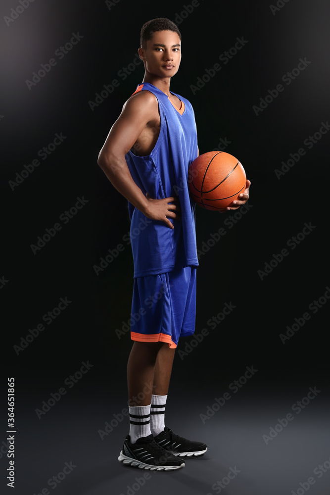 Wall mural young african-american basketball player on dark background