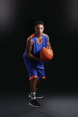 Young African-American basketball player on dark background
