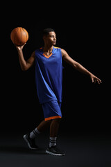 Fototapeta premium Young African-American basketball player on dark background