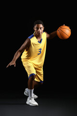 Naklejka premium Young African-American basketball player on dark background
