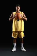 Young African-American basketball player on dark background
