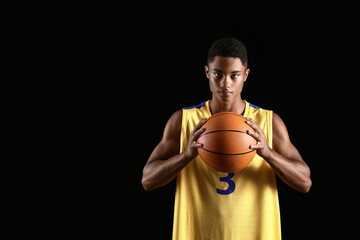 Young African-American basketball player on dark background
