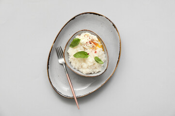 Bowl with boiled rice and egg on light background