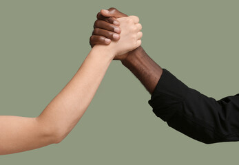 Caucasian woman and African-American man holding hands together on color background. Racism concept