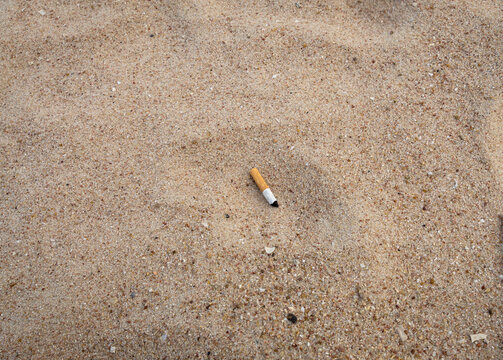 close up view of used cigarette butt left on sand ground , pollution , for background