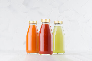 Tomato, carrot, green vegetable juices set in glass bottles with cap mock up in row on white wood...