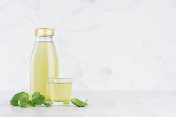 Fresh vegetable green spinach juice in glass bottle template with glass, leaves on wood table and white background with copy space.