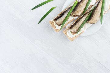 Organic season sandwiches on dry wheat crispbread with sprats fish, green onion, cheese on white...