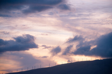 Sunset Color sky with the mountain ridge and wind turbine, renewal energy