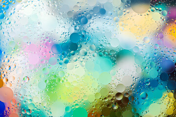 Close-up of the movement of oil droplets on the water surface. Colorful abstract macro background...